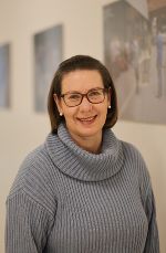 Porträt einer Person mit kurzen, dunklen Haaren und freundlichem Ausdruck.