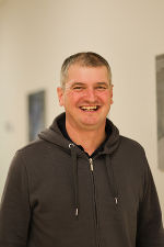 Lachende Person mit dunklem Hoodie. Nahaufnahme des Kopfes und der Schultern.