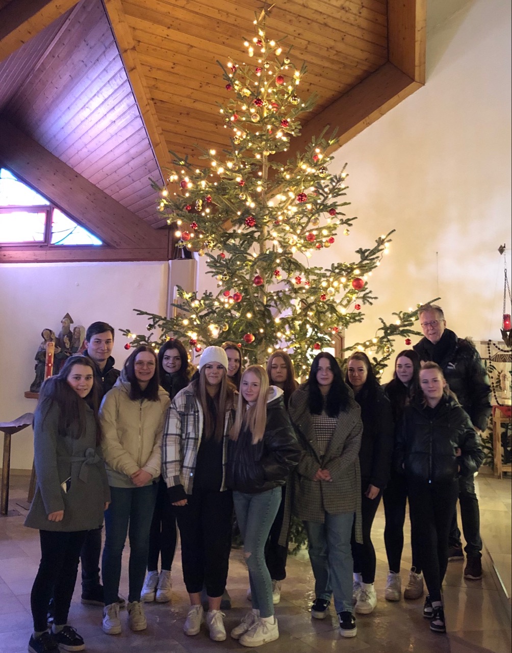 Die 1aVA-Klasse mit Herrn Mag. Walter Drexler vor dem weihnachtlich geschmückten Christbaum in der Pfarrkirche Mitterdorf