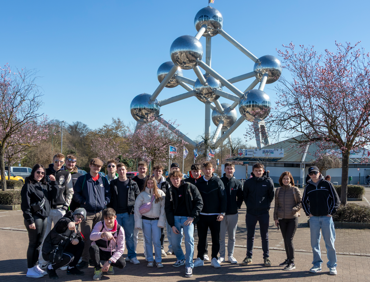 Lachende Schülergruppe mit Lehrerin Veronika Puntigam- im Hintergrund das Atomium (Symbol für das Atomzeitalter, den technologischen Fortschritt und den Frieden)
